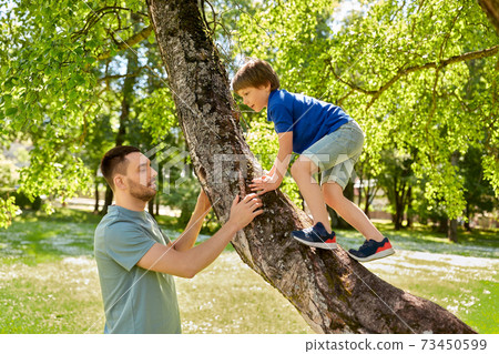 happy father with son climbing tree in summer park happy father with son climbing tree in summer park 73450599