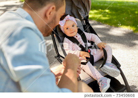 happy father with child in stroller at summer park happy father with child in stroller at summer park 73450608