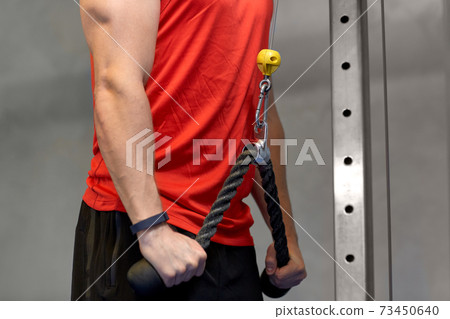 close up of man exercising on cable machine in gym close up of man exercising on cable machine in gym 73450640
