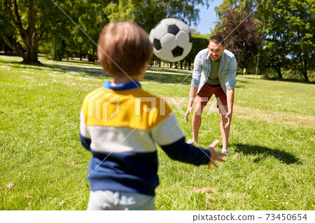 father with little son playing soccer at park 73450654