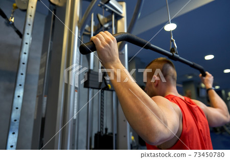 close up of man exercising on cable machine in gym 73450780