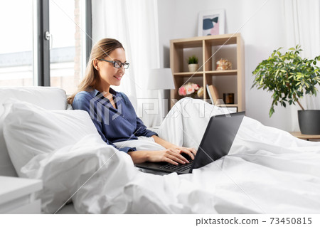 young woman with laptop in bed at home bedroom young woman with laptop in bed at home bedroom 73450815