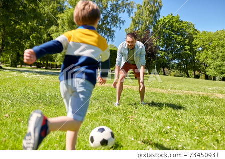 father with little son playing soccer at park 73450931