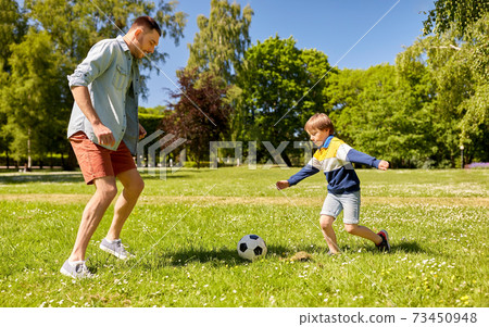 father with little son playing soccer at park 73450948
