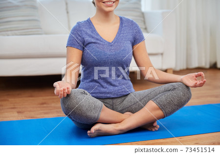 woman meditating in lotus pose at home woman meditating in lotus pose at home 73451514