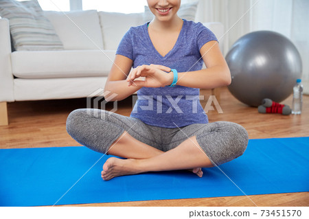 woman with fitness tracker doing yoga at home woman with fitness tracker doing yoga at home 73451570