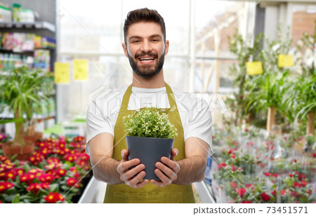 smiling male gardener with flower in pot at shop 73451571