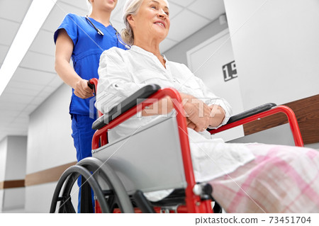 nurse with senior patient in wheelchair at clinic 73451704