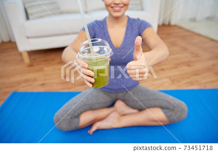 happy woman with cup of smoothie showing thumbs up 73451718