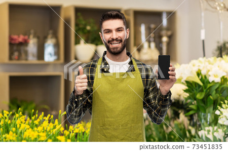 seller with phone shows thumbs up at flower shop 73451835