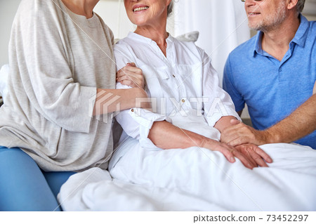 happy family visiting senior woman at hospital 73452297