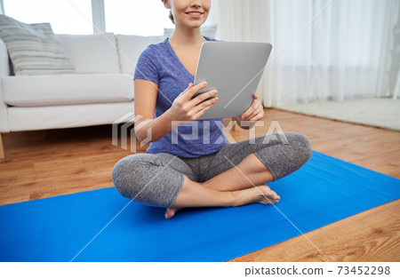 woman with tablet pc computer doing yoga at home 73452298