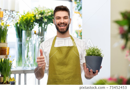 happy male seller with flower showing thumbs up happy male seller with flower showing thumbs up 73452453