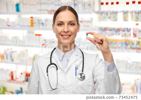 female doctor holding medicine pill at pharmacy female doctor holding medicine pill at pharmacy 73452475