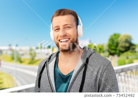 happy smiling man in headphones listening to music 73452492