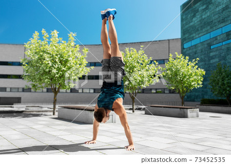 young man exercising and doing handstand outdoors 73452535