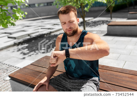 man with smart watch sitting on bench 73452544