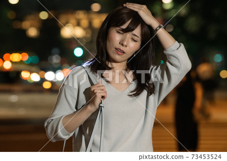 Image of a Japanese woman walking in the office district at night and a business woman returning from overtime 73453524