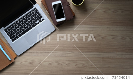 Top view of stylish workspace with laptop, smart phone, coffee cup, notebook and copy space on wooden table. Top view of stylish workspace with laptop, smart phone, coffee cup, notebook and copy space on wooden table. 73454014