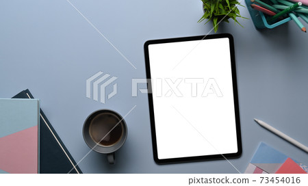 Top view of creative designer or stylish workspace with mock up digital tablet, notebook, coffee cup and plant on gray table. Top view of creative designer or stylish workspace with mock up digital tablet, notebook, coffee cup and plant on gray table. 73454016