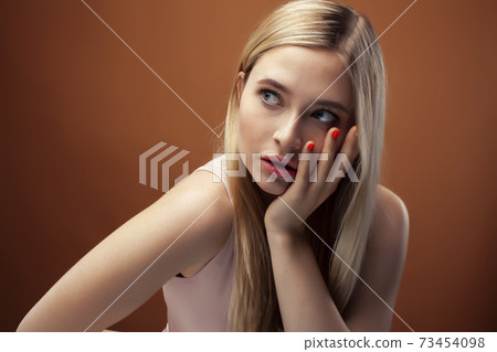 young pretty girl with blond hair posing cheerful on brown background, lifestyle people concept 73454098