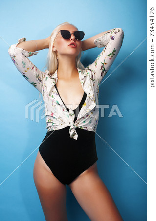 young pretty blond woman in swimsuit and sunglasses posing cheerful on blue background, lifestyle people on vacation concept 73454126