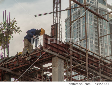 Construction Worker Welding soldering metal girders and Sparks. 73454645
