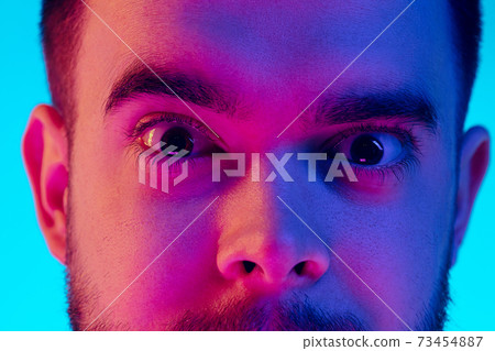 Caucasian man's portrait isolated on blue studio background in neon light. Concept of human emotions, facial expression, sales, ad. Caucasian man's portrait isolated on blue studio background in neon light. Concept of human emotions, facial expression, sales, ad. 73454887
