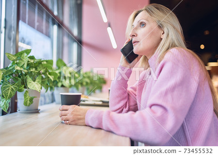 Adalt charming woman calling with cell telephone while sitting alone in coffee shop 73455532