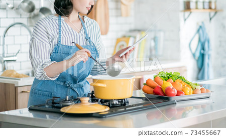 A housewife using a tablet in the kitchen A housewife using a tablet in the kitchen 73455667