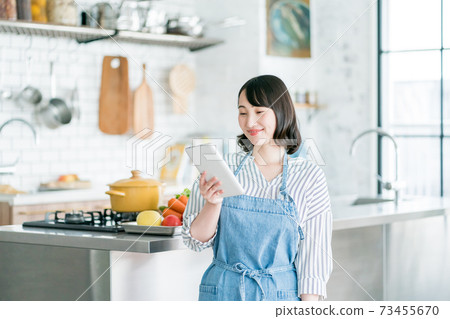 A housewife using a tablet in the kitchen A housewife using a tablet in the kitchen 73455670