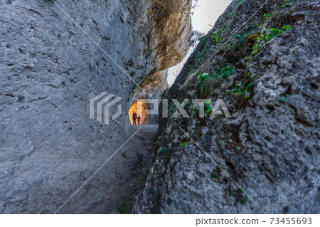 Two unrecognizable persons walking through the rocks tunnel Two unrecognizable persons walking through the rocks tunnel 73455693