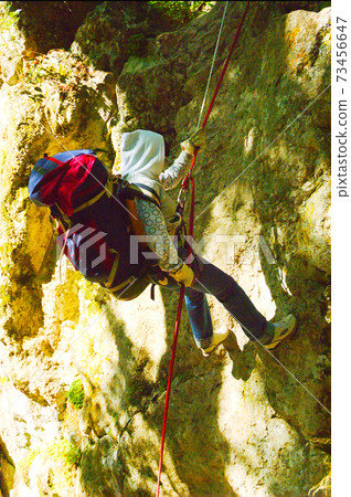 Woman climbing on steep the mountain slope 73456647