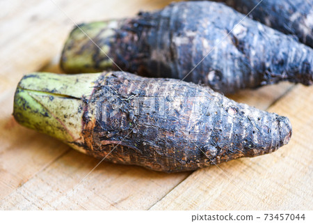 Taro root ready to cook, Raw organic brown taro on wooden table. Taro root ready to cook, Raw organic brown taro on wooden table. 73457044