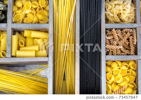 assortment of pasta in a wooden box with cells for different types of products top view on the traditional Italian food. 73457847