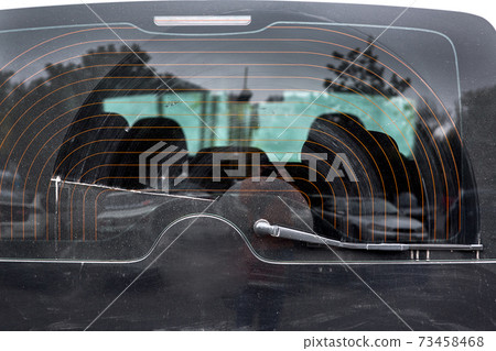 dirty car glass in a layer of dust wiped by a wiper, close up of the rear window of the heated black car. dirty car glass in a layer of dust wiped by a wiper, close up of the rear window of the heated black car. 73458468
