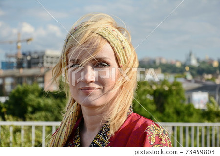 A woman in 1960 hippie style clothes poses outdoors 73459803