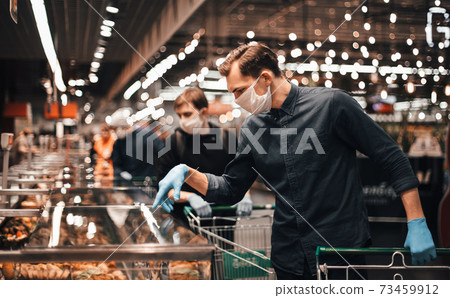 customer in protective gloves choosing products in a supermarket. 73459912