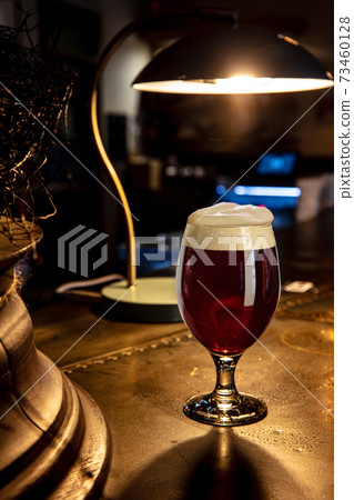 Glass of stout beer on wooden table in warm light of bar Glass of stout beer on wooden table in warm light of bar 73460128