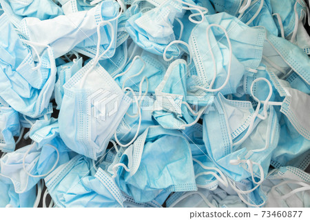 Texture of wrinkled protective face masks, discarded dirty trash. 73460877