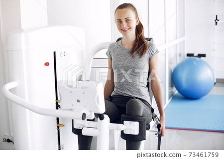 Young lady doing exercises on simulator in phisiotherapy room 73461759