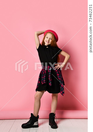 Ginger teenage girl in black dress, checkered shirt on waist, red hat and choker. She smiling, posing on pink background. Close up Ginger teenage girl in black dress, checkered shirt on waist, red hat and choker. She smiling, posing on pink background. Close up 73462251