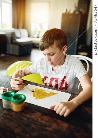 The boy is sitting at the table at home and 73463647