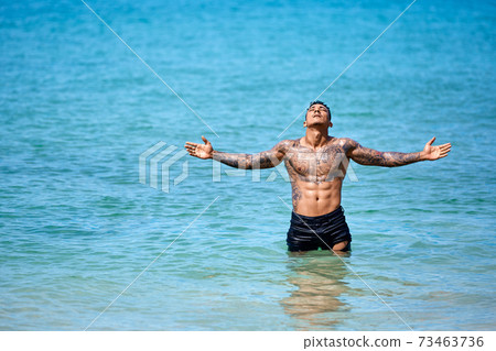 Athletic young tattooed guy at the beach 73463736