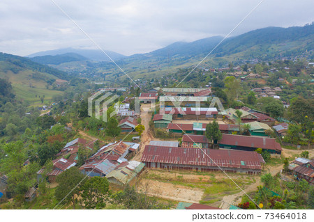 Aerial top view of immigrant refugees residential village houses in countryside, rural area. Local community houses in urban town near natural forest on mountain hills, Tak, Thailand. Evacuation. Aerial top view of immigrant refugees residential village houses in countryside, rural area. Local community houses in urban town near natural forest on mountain hills, Tak, Thailand. Evacuation. 73464018