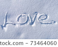 Love word written on white clean snow surface. Love lettering for romantic occasions - proposal, wedding day, valentines day. Sunny winter day and glowing snow texture 73464060