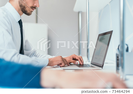 close up. serious business man is working on his laptop in the office. 73464294