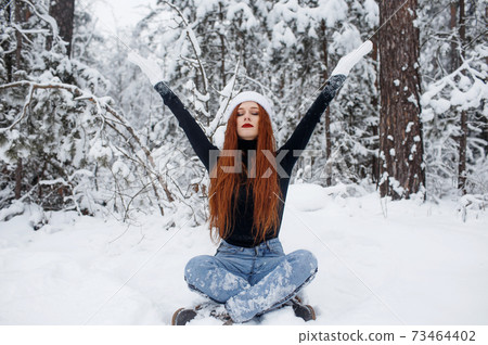 a girl with bright red hair meditates sitting in the forest. relaxing in nature. a girl with bright red hair meditates sitting in the forest. relaxing in nature. 73464402