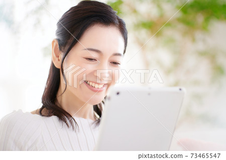 操作平板電腦在客廳裡的中年女人 73465547