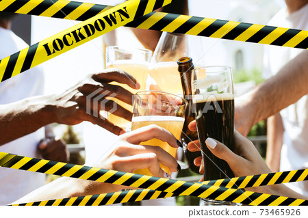 Close up hands clinking glasses of beer at bar with bounding tapes Lockdown, Coronavirus, Quarantine, Warning - closing bars and nightclubs during pandemic Close up hands clinking glasses of beer at bar with bounding tapes Lockdown, Coronavirus, Quarantine, Warning - closing bars and nightclubs during pandemic 73465926